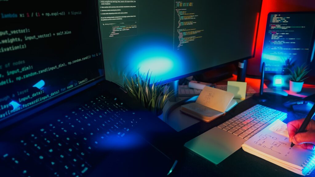 Computer screens displaying code with neon lighting. – Building WordPress Pages and Design Systems with Elementor’s Angie AI